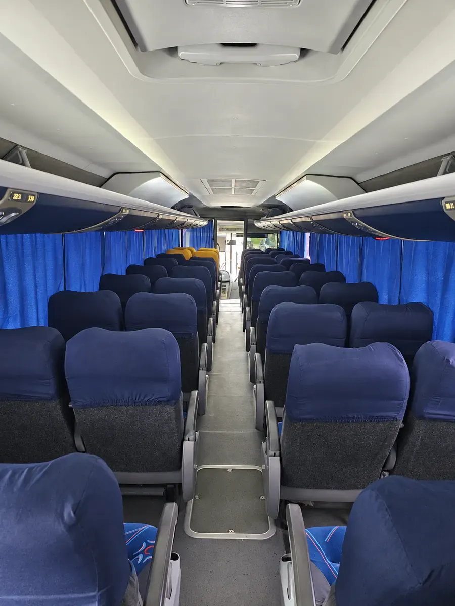 Interior da unidade Locart 3505 com corredor central, poltronas em configuração dois mais dois, cortinas e maleiros internos