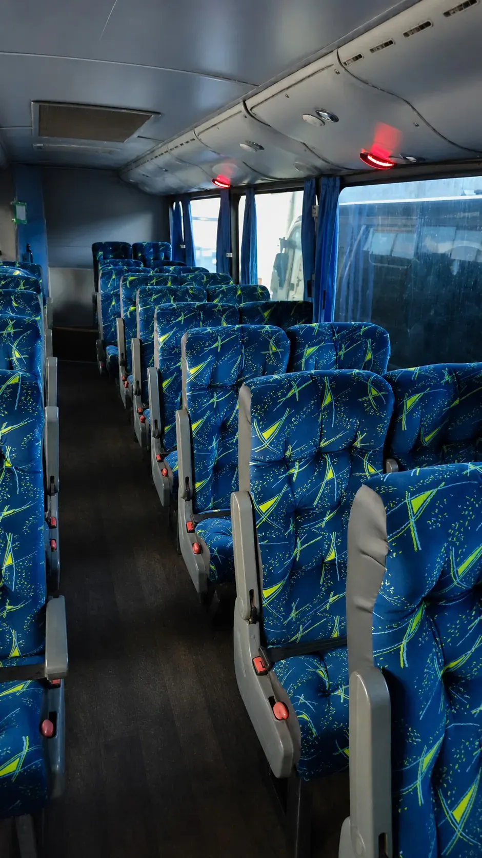 Interior azul enviado pela empresa, com corredor central, poltronas e cortinas