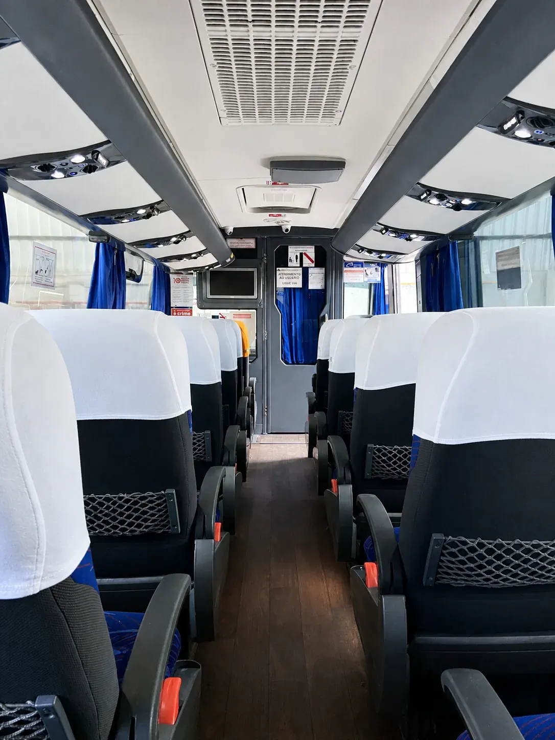 Interior claro enviado pela empresa, com corredor central, poltronas em configuração dois mais dois e cortinas